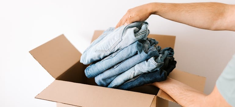 a person placing folded jeans in a box
