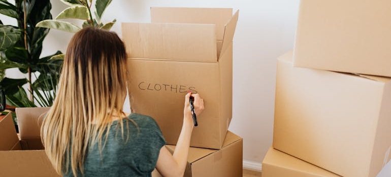 A woman labeling a box Clothing before storing away winter clothes