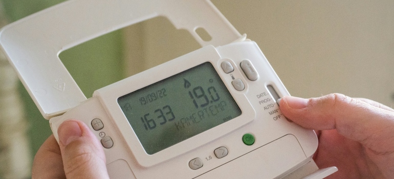 A person holding a programmable thermostat