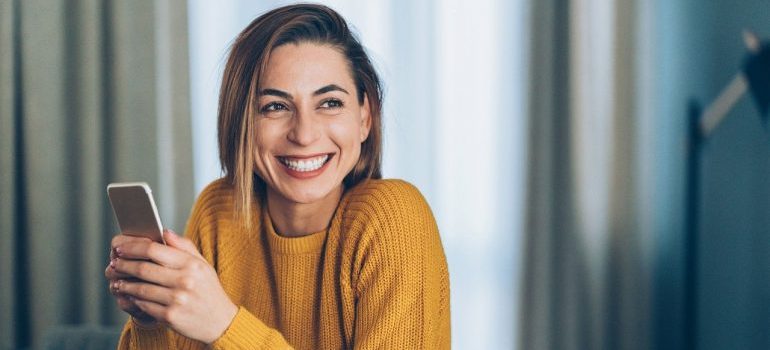 A woman holding a phone and smiling.