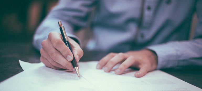 A person signing a contract while renting self-storage Marysville WA.