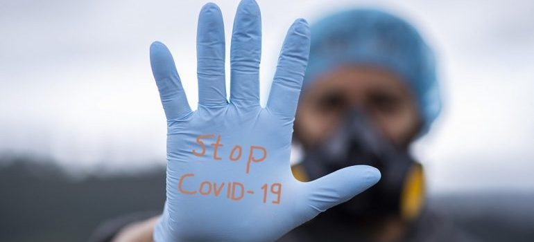 A man wearing a glove with a stop covid-19 inscription.
