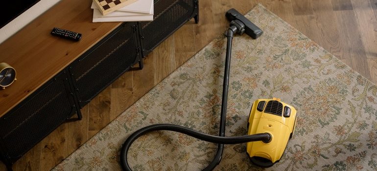 Person vaccuming before they pack rugs and carpets for storage.