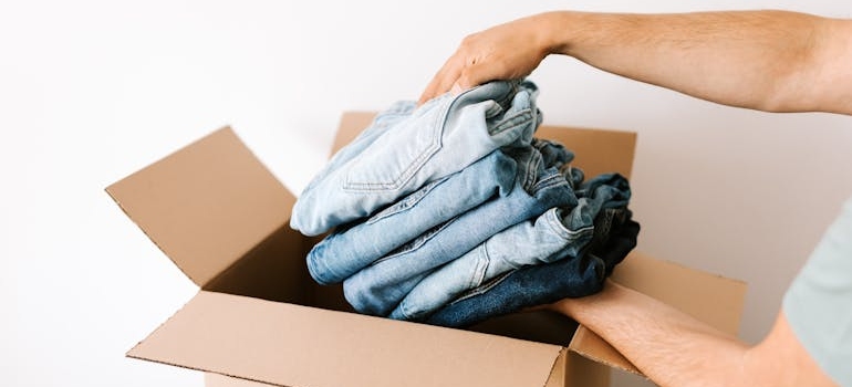 A person packing jeans from a wardrobe for moving