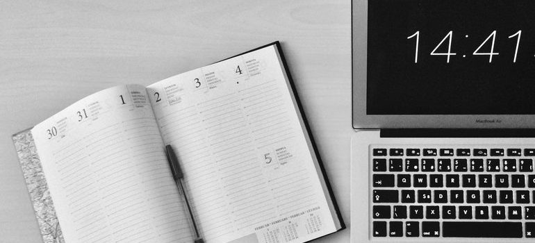 Open notebook next to a laptop.