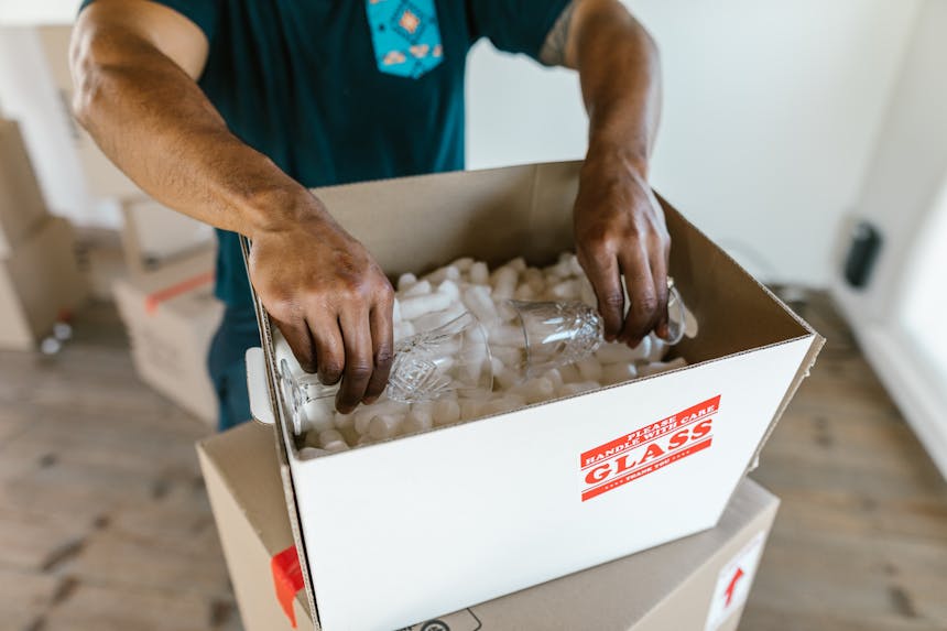 Person Packing Glasses Inside a cardboard Box
