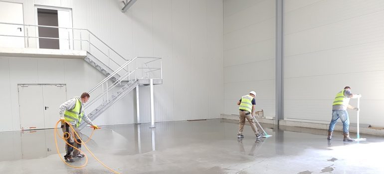 Three men cleaning a warehouse.