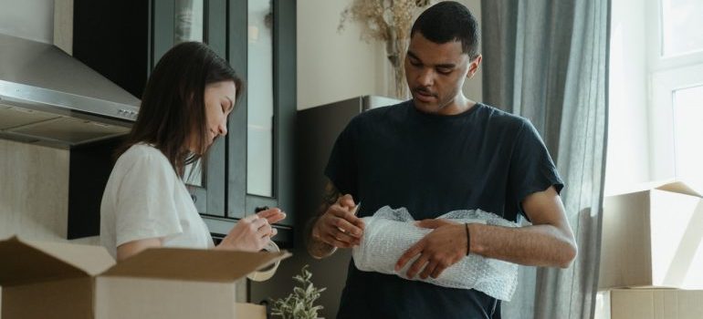 Couple packing and storing kitchenware and dishes