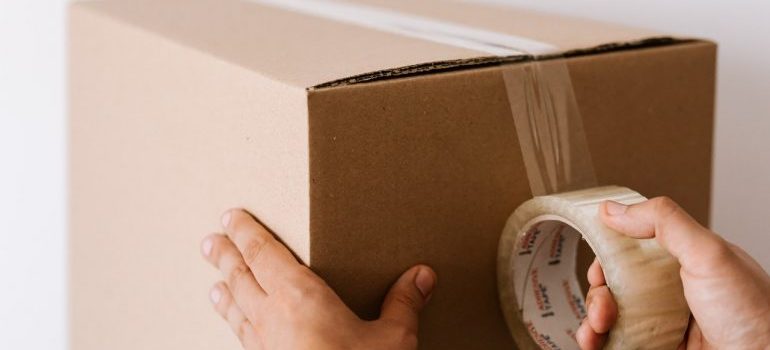 Man packing a box instead of deciding to hire professional packers when storing