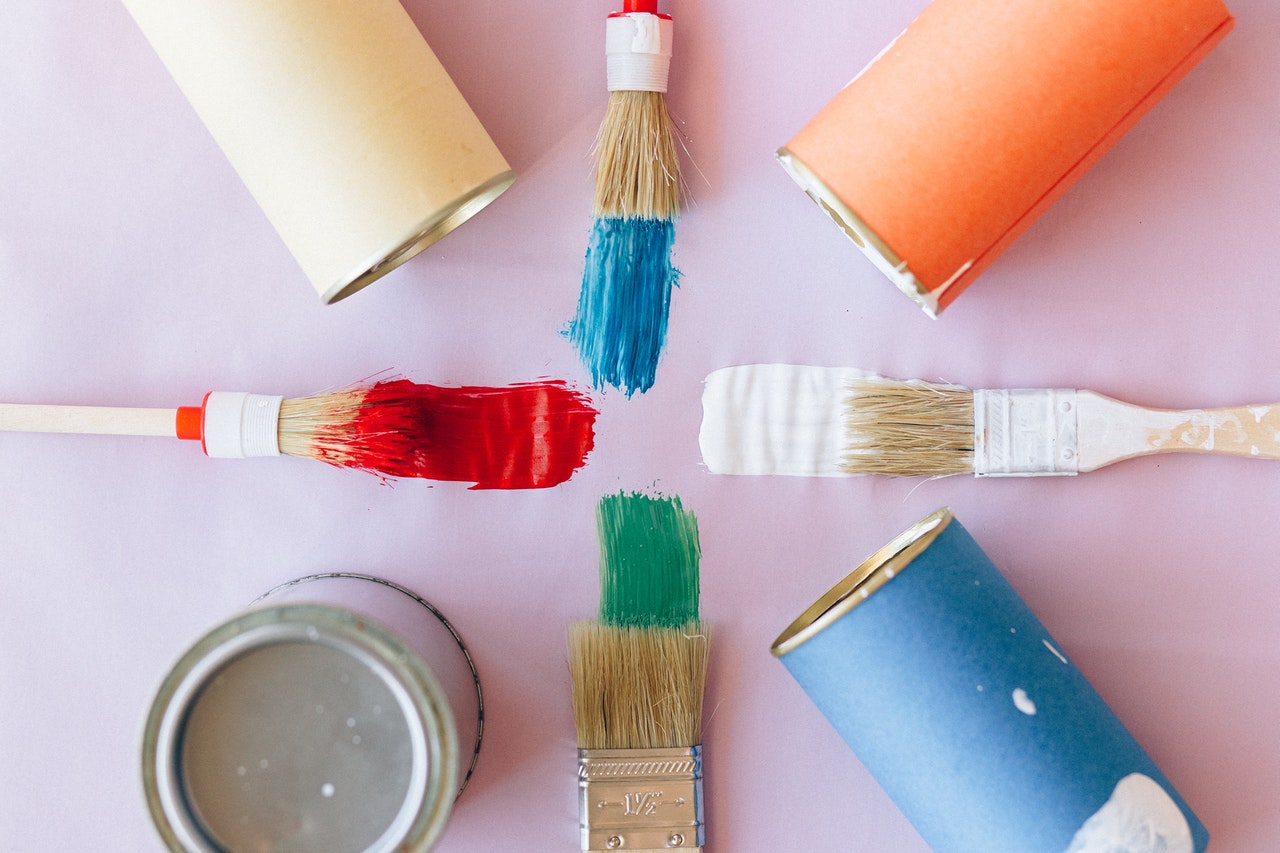 Four paint brushes amid paints