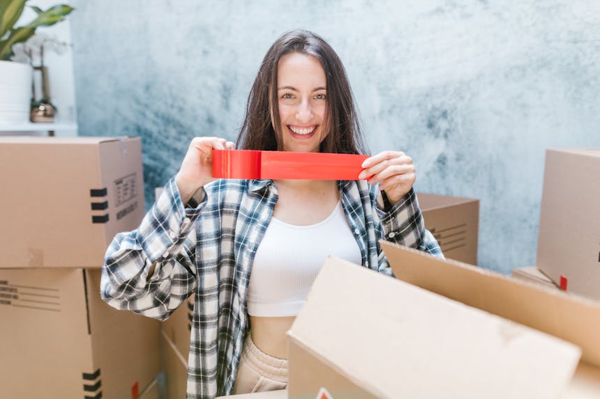 Woman in Checkered Long Sleeves Holding a Red Packaging Tape