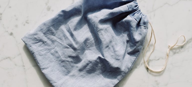 Empty textile blue bag with drawstrings placed on table in light room