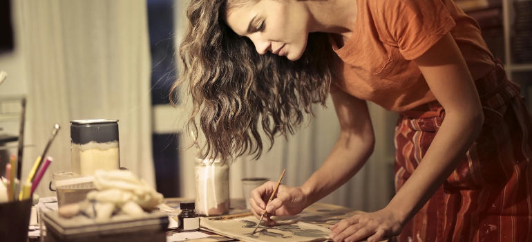 Creative female artisan drawing in workshop while her self storage helps self-discipline