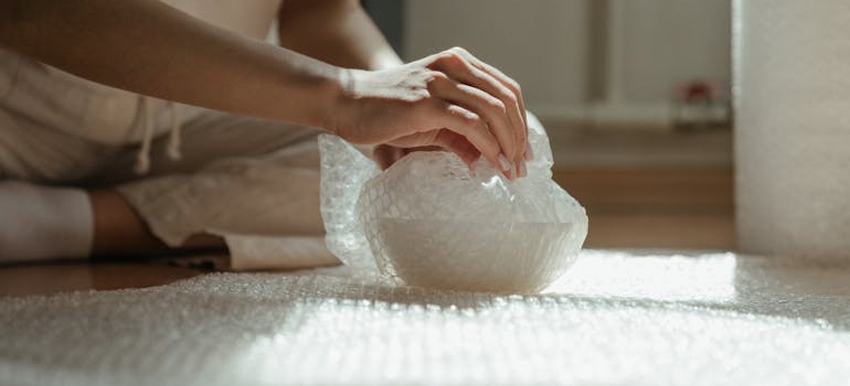 A woman wraping porcelain in bubble wrap