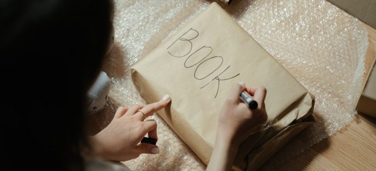 Woman packing books since they are one of the most commong things people store away
