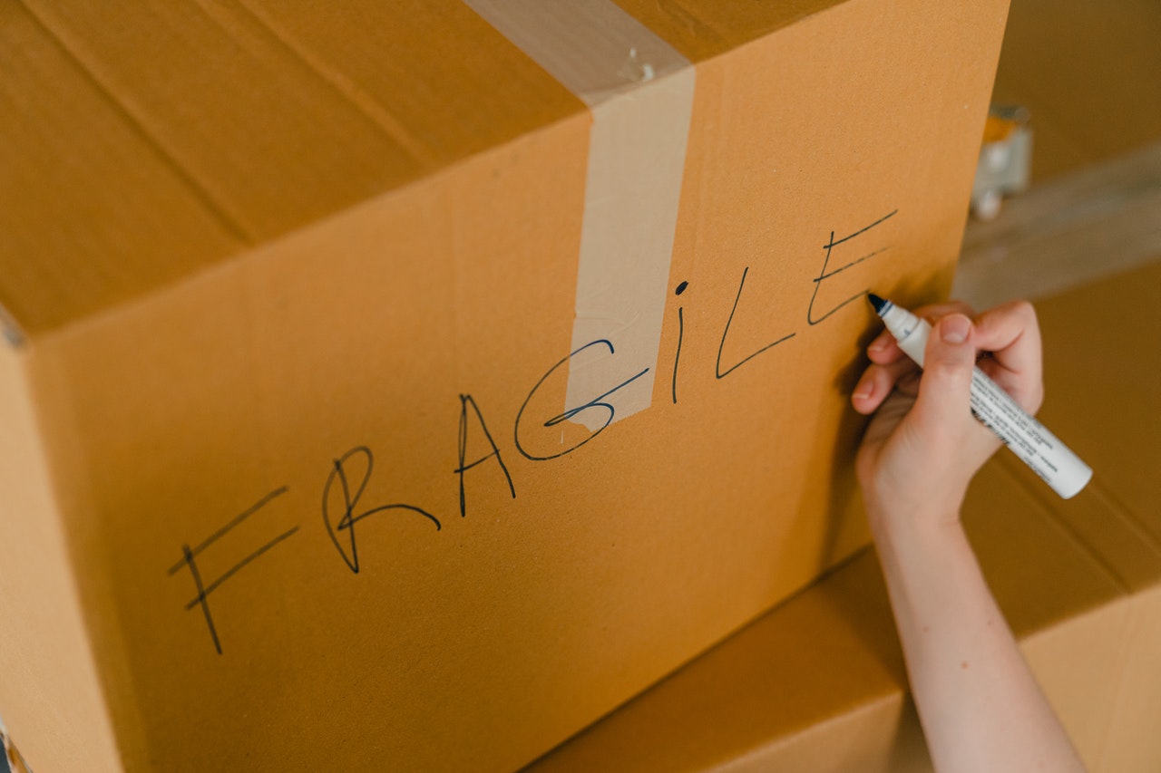 Person writing fragile on a box