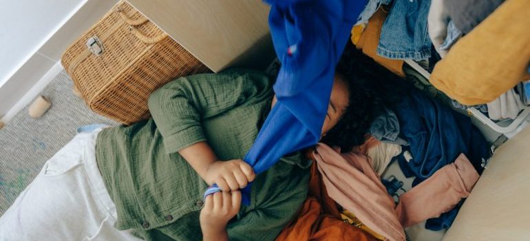Person decluttering clothes after reading a guide on downsizing your Seattle home