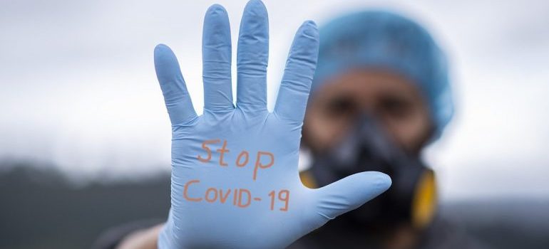 A man wearing a glove with the writing stop covid-19.