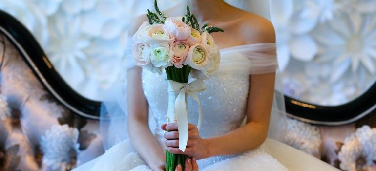 A woman holding a bouquet, sitting in a wedding dress.