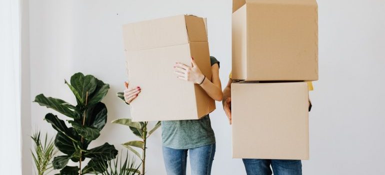 Two people carrying heavy boxes symbolizing the risks of doing a last minute move