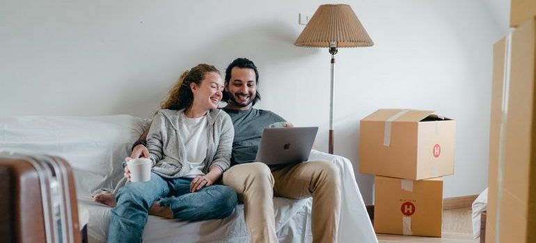 Couple sitting on sofa and reading on laptop about the risks of doing a last minute move