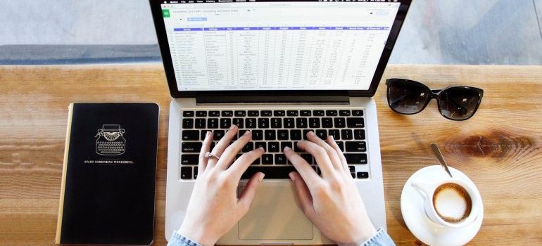 A woman typing on a laptop in order to create an inventory for your storage.