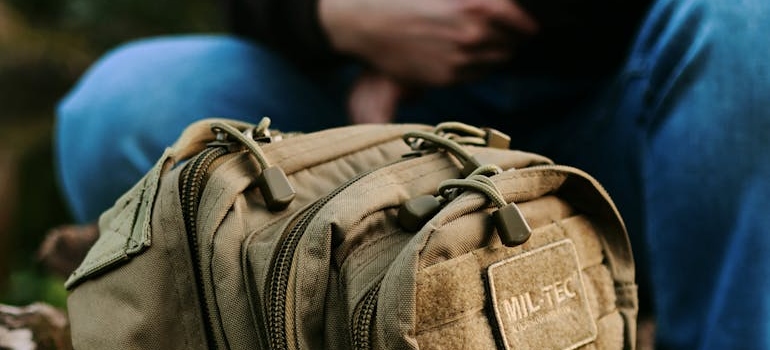 A man sitting next to a mil-tec backpack
