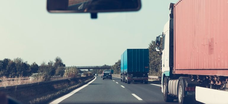 Person on the road, driving next to moving trucks.