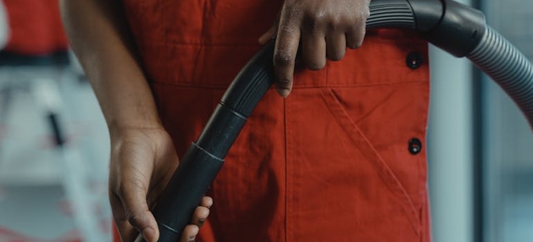 Person in Red Jumper Holding a Vacuum Hose