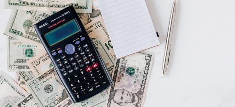 A notepad and a calculator on top of dollar bills.