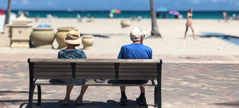 Elderly couple on a bench by the beach.