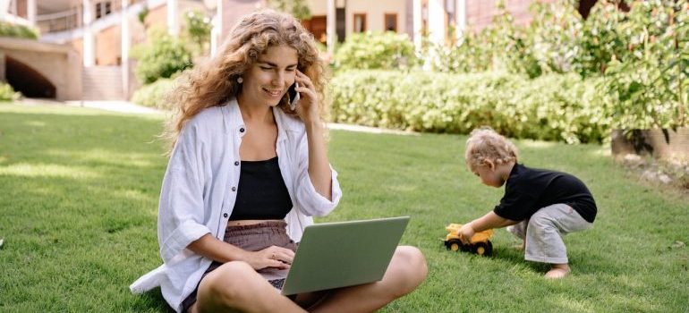 A woman making a phonecall while her child plays next to her.