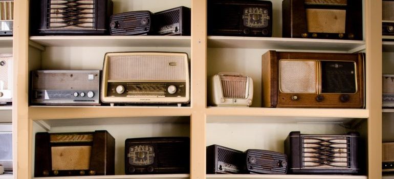 Old radios arranged on wooden shelves.