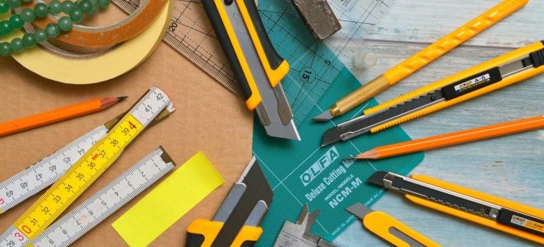Pens, scalpels, and rulers on a wooden surface.