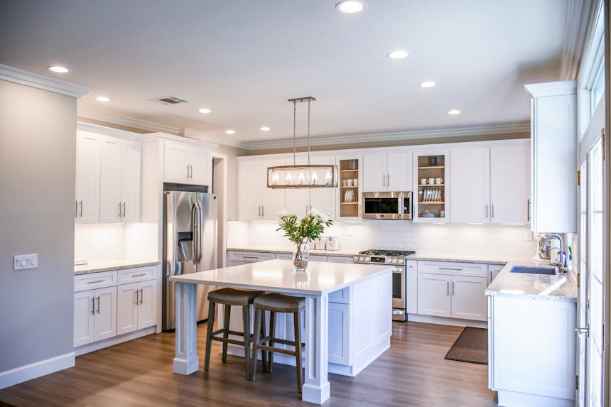 A clean white kitchen with cabinets and appliances.
