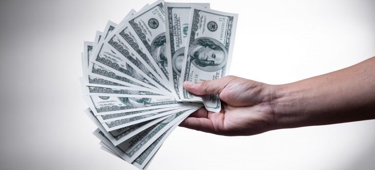 A hand holding dollar bills - why sporting goods stores need self-storage