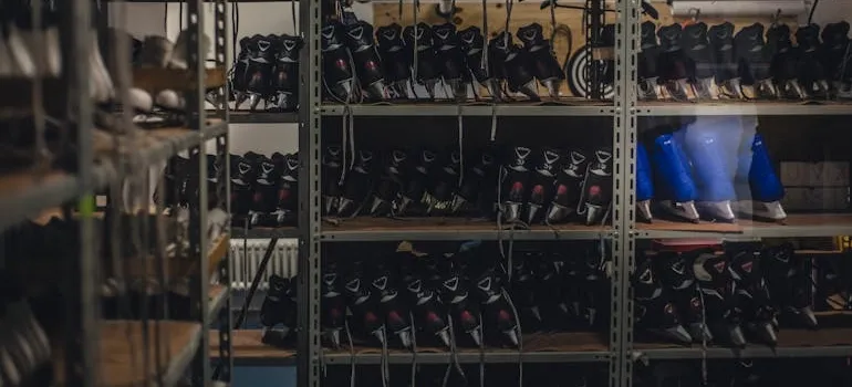 Black and blue ice skates on gray metal shelf inside white room
