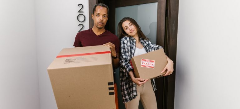 A stunted couple holding moving boxes