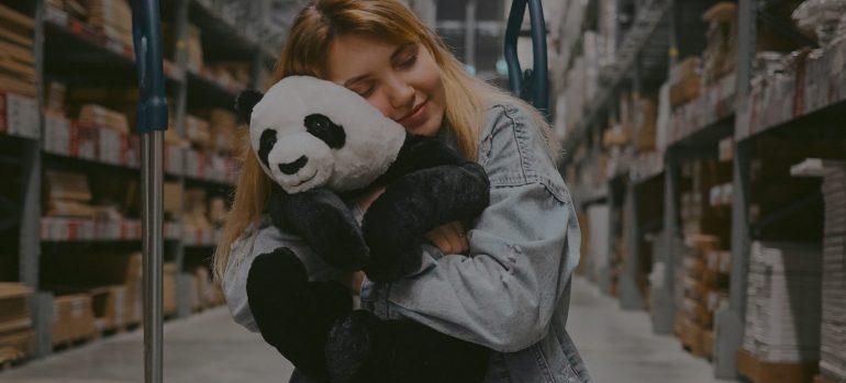 A girl in a storage unit hugging a Teddy Bear - hobbies that benefit form renting self storage 
