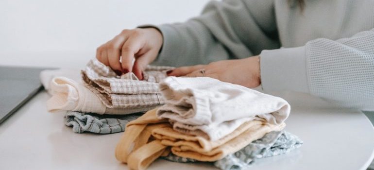 A woman sorts baby things out by following the tips for organizing your nursery
