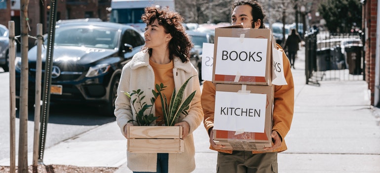 Couple carrying boxes and plants