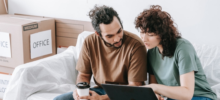 a man and a woman are looking at a laptop while preparing for settling in Mill Creek WA