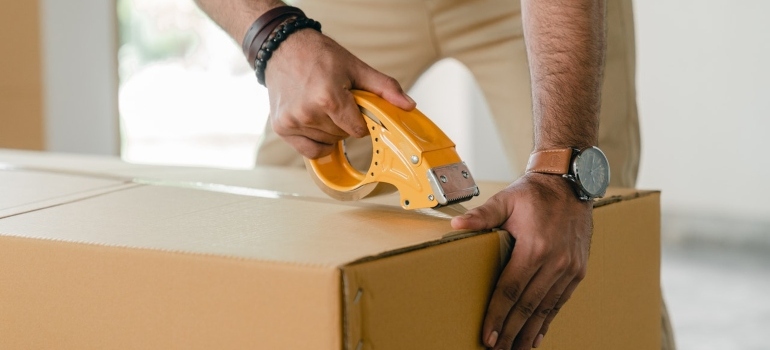 a man taping a cardboard box