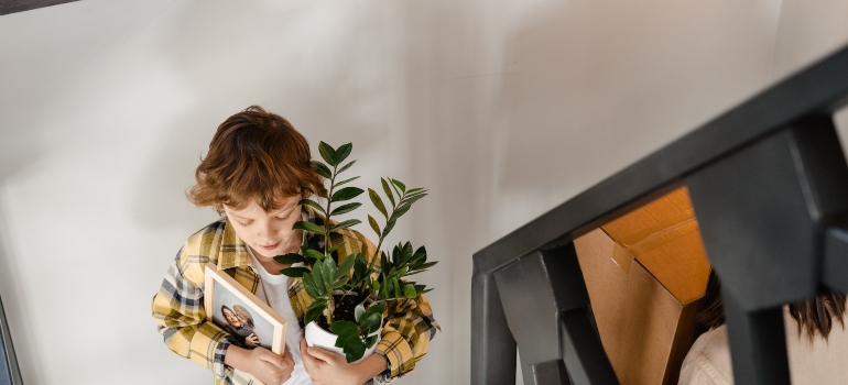 young boy carrying plant and a photo