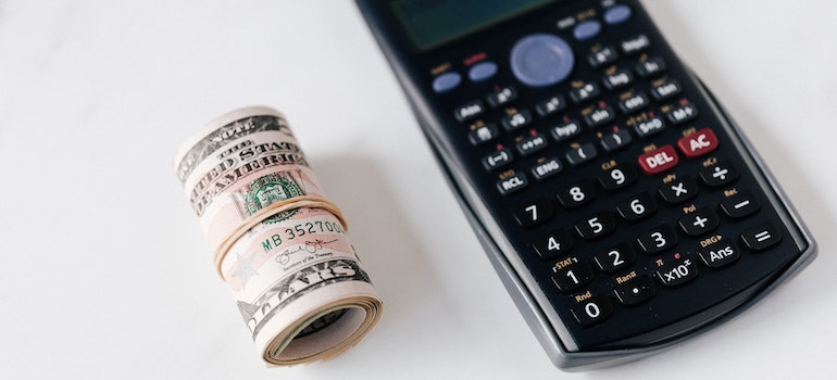 Calculator with multicolored buttons and a roll of dollar bills on a table