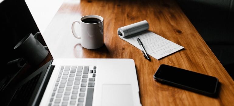 Laptop, phone, pen, paper and a coffee mug