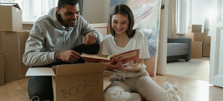 A couple sitting among moving boxes and looking through photos
