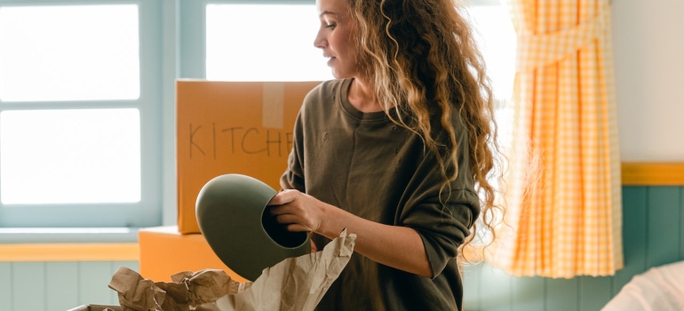 a woman packing a vase and weighing the pros and cons of home storage