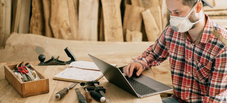 Man researchinhg on his laptop with tools on the table