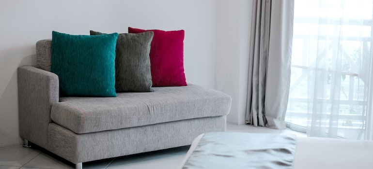 a sofa with pillows next to a curtain